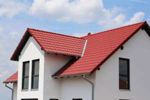 Das Bild zeigt ein Wohnhaus mit fertig gestellter Fassade in weiß. Die Dachziegel des Hauses sind in rot gewählt worden.