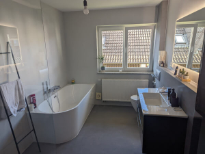 Das Bild zeigt ein fugenloses Badezimmer. In dem Ausschnitt ist eine fliesenloses Badezimmer mit Badewanne und Waschtisch zu sehen.
